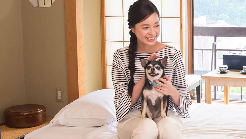 岐阜県・下呂温泉の愛犬と泊まれる宿「紅葉館 別館わん泊亭」の和室で愛犬をなでながら過ごす女性