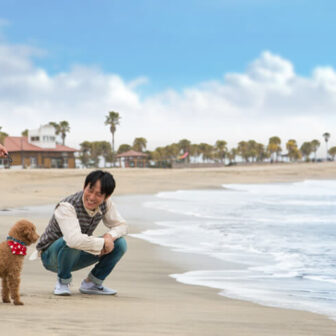 宮崎 シーガイア・フォレスト・コテージ前の海辺を犬と散歩する夫婦。ペット同伴で海を楽しめる宿泊体験