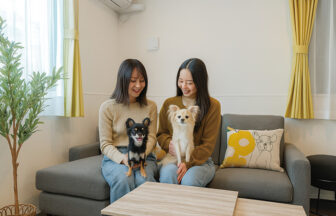 ペット同伴でくつろげるリビング。ソファに座る女性2人と、楽しそうに抱かれる小型犬の様子｜大阪府大阪ベイエリアの一棟貸しの犬と泊まれる宿 ｜専用駐車場付き一棟貸しの宿｜カーサステラ 8 by リエゾン