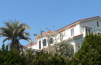 静岡県にある宿・ガラスの仔犬の外観。青空に映える白い南欧風の建物と周囲の緑が印象的なペットと泊まれる宿。