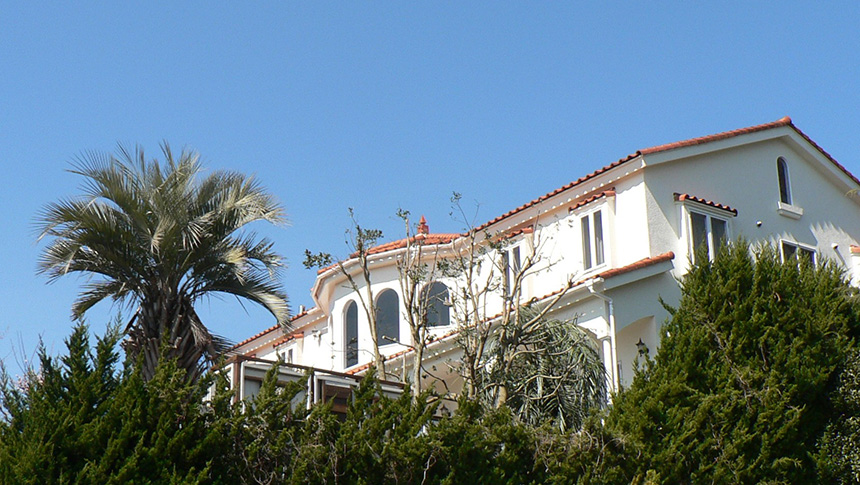 静岡県にある宿・ガラスの仔犬の外観。青空に映える白い南欧風の建物と周囲の緑が印象的なペットと泊まれる宿。