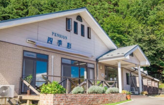 山梨県・河口湖の愛犬と泊まれる宿「ペットと泊れる富士山眺望の宿 四季彩」の緑豊かな森を背にしたペンション外観