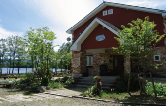 福島県裏磐梯の曽原湖畔にある、赤い壁と石積みのエントランスが特徴的な「湖畔のぬくもりの宿 ラーラ」の外観。うさぎや小鳥などの小動物と泊まれるアットホームなペンションです。