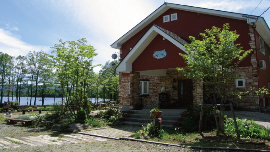 福島県裏磐梯の曽原湖畔にある、赤い壁と石積みのエントランスが特徴的な「湖畔のぬくもりの宿 ラーラ」の外観。うさぎや小鳥などの小動物と泊まれるアットホームなペンションです。