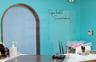 福島県いわき湯本温泉「スパホテル スミレ館」のフロント・レセプション。爽やかな水色の壁と可愛らしい犬のマスコットが出迎える、ペット連れに優しい受付カウンター。