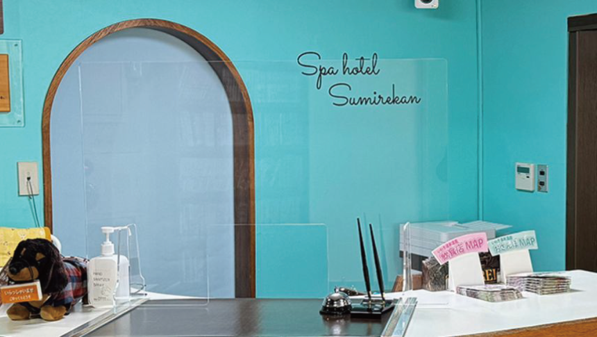 福島県いわき湯本温泉「スパホテル スミレ館」のフロント・レセプション。爽やかな水色の壁と可愛らしい犬のマスコットが出迎える、ペット連れに優しい受付カウンター。