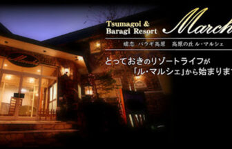 群馬県・嬬恋の犬と泊まれる宿「ル・マルシェ」｜夜の静寂に浮かび上がる、ライトアップされた石造りのペンション「ル・マルシェ」。温かな光に包まれた入り口と、エレガントなロゴ、そして「とっておきのリゾートライフ」の始まりを予感させるキャッチコピー。