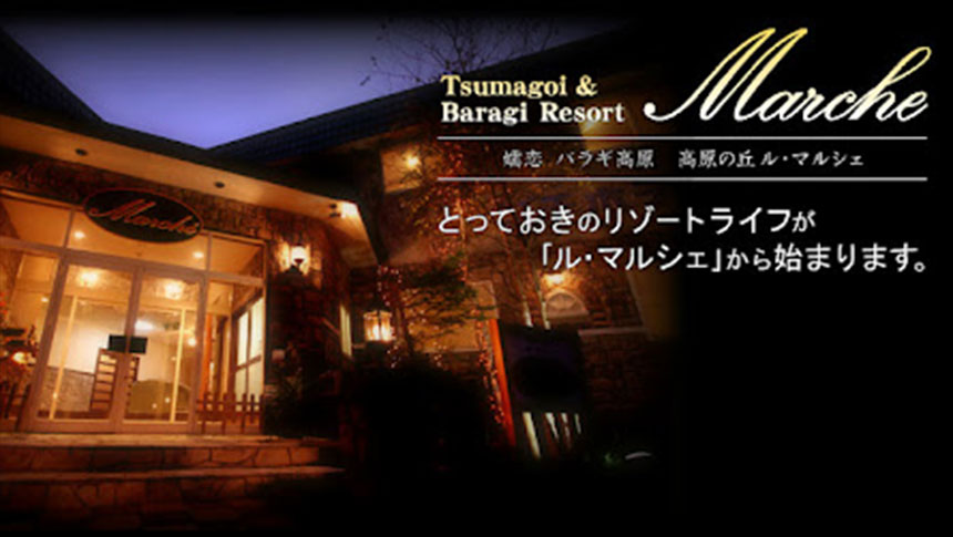 群馬県・嬬恋の犬と泊まれる宿「ル・マルシェ」｜夜の静寂に浮かび上がる、ライトアップされた石造りのペンション「ル・マルシェ」。温かな光に包まれた入り口と、エレガントなロゴ、そして「とっておきのリゾートライフ」の始まりを予感させるキャッチコピー。
