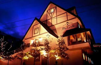 新潟県・南魚沼市の犬と泊まれる宿「スキー・スノボとペットの宿　アルミュール」｜夜の雪景色の中に建つ、ライトアップされた新潟県・湯沢のペンション「アルミュール」の外観