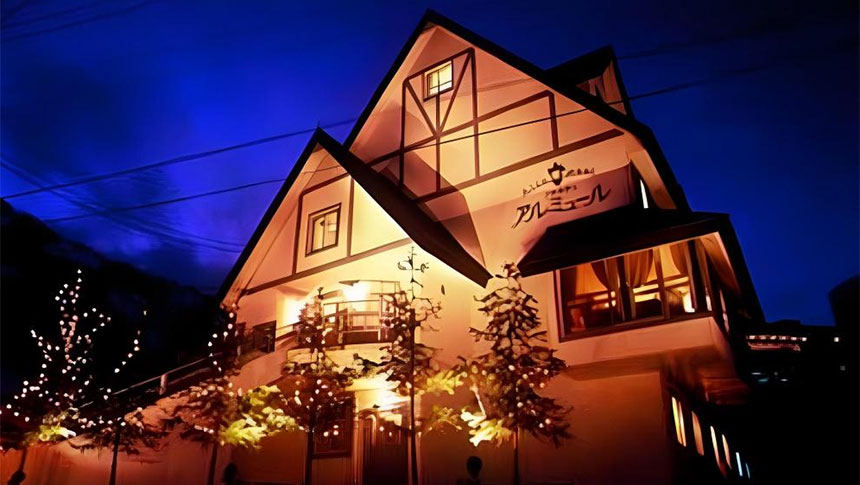 新潟県・南魚沼市の犬と泊まれる宿「スキー・スノボとペットの宿　アルミュール」｜夜の雪景色の中に建つ、ライトアップされた新潟県・湯沢のペンション「アルミュール」の外観