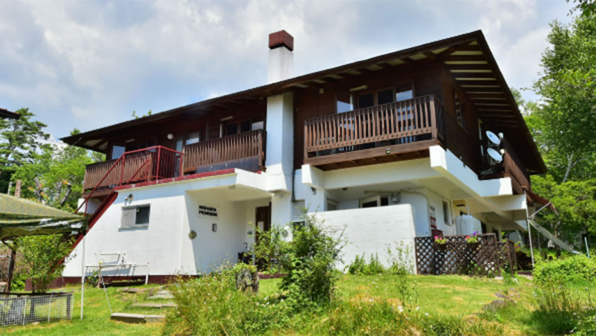 長野県・八ヶ岳中央高原にある犬と泊まれる宿「のはらペンション」の和モダンな外観。1階は白壁、2階は木の温もりを感じさせるデザインで、青空と緑豊かな自然に囲まれた佇まい