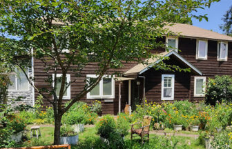 静岡県・伊豆高原の犬と泊まれる宿「ペンションfigtree（フィグツリー）」｜色とりどりの花々が咲き誇る豊かな庭と、その奥に佇む白い窓枠が特徴的な2階建ての木造ログハウス