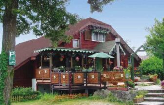 鳥取県大山にあるペットと泊まれる宿『ペンションブーメラン』の赤い木造の外観と、花に囲まれた開放的なウッドデッキテラス