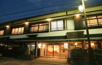 夜の静寂に包まれる皆生温泉・海潮園。温かな光が漏れる客室の窓と、文人に愛された老舗旅館の落ち着いた佇まい。