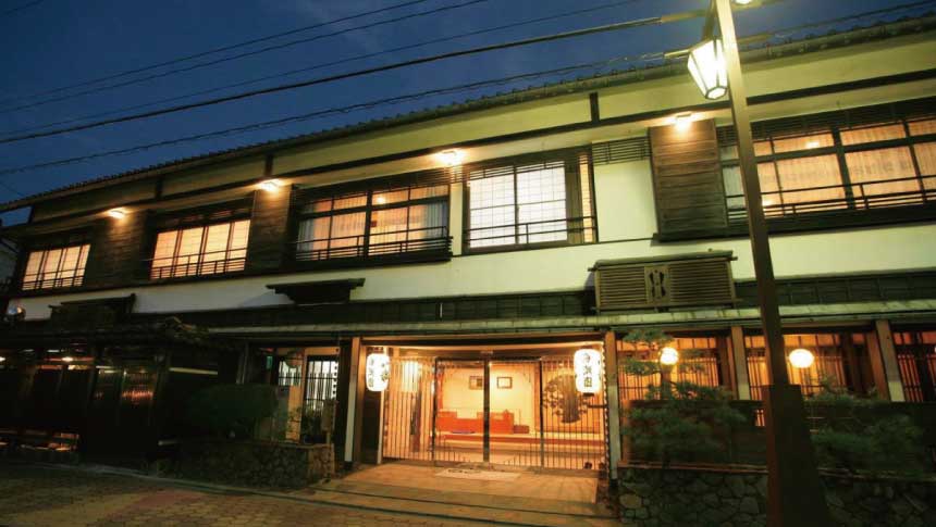 夜の静寂に包まれる皆生温泉・海潮園。温かな光が漏れる客室の窓と、文人に愛された老舗旅館の落ち着いた佇まい。