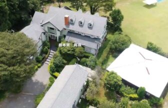 ペンションベルバードの全景空撮。豊かな森に囲まれた白い洋館と広大な芝生広場