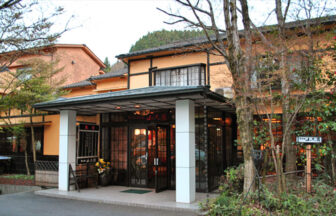 大分県・宝泉寺温泉にある犬と泊まれる旅館「山光園」｜落ち着いた和の風情が漂う「山光園」の正面玄関。周囲を木々に囲まれ、夜には提灯の明かりが灯る、ペットと一緒に寛げる温泉旅館の入り口。｜ペット宿ドットコム