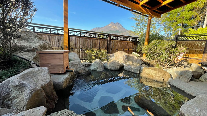 大分県湯布院の犬と泊まれる宿「由布院 吾亦紅（われもこう）」の露天風呂。岩造りの湯船の向こうに、新緑に映える由布岳の絶景が広がる様子