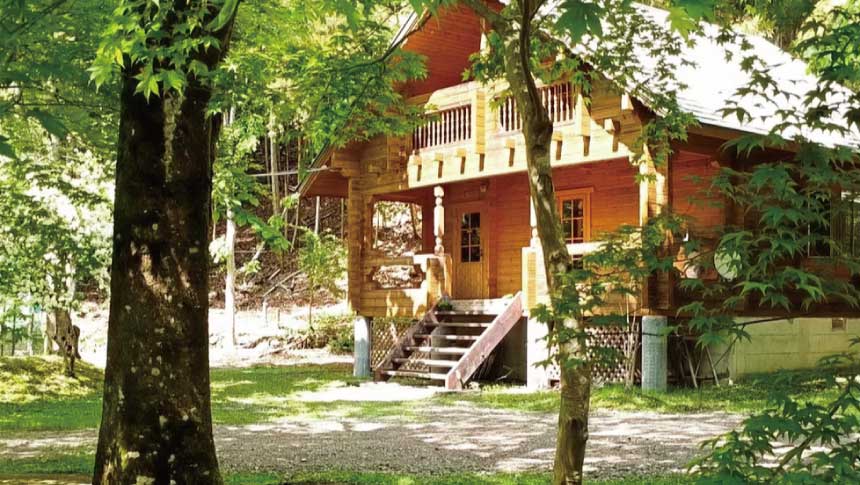 鳥取県鳥取市にあるペットと泊まれる宿「フォレストリア用瀬」のフィンランド製ログハウス外観。豊かな新緑に囲まれた静かなコテージ。