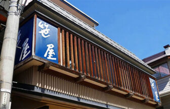 和風建築の店舗「笹屋」の外観。青い看板と温かみのある木の格子が並ぶ店構え｜長野県野沢温泉の犬と泊まれる宿｜野沢温泉　笹屋