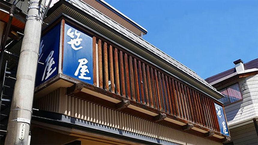 和風建築の店舗「笹屋」の外観。青い看板と温かみのある木の格子が並ぶ店構え｜長野県野沢温泉の犬と泊まれる宿｜野沢温泉　笹屋