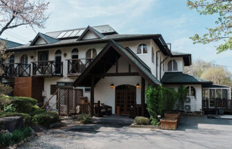 山梨県・小淵沢にある「ロッジ・アトリエ」の外観。三角屋根のエントランスと白い壁が特徴的な洋風の建物