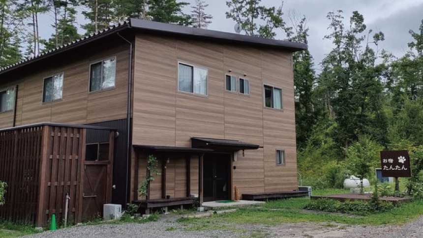 安曇野・穂高温泉郷にあるペット専用宿「お宿たんたん」の建物外観と周囲の森。
