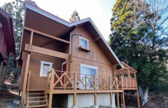 緑豊かな自然に囲まれた「ゆいま～るるり渓」の建物外観。広いウッドデッキ付きの木造コテージ。