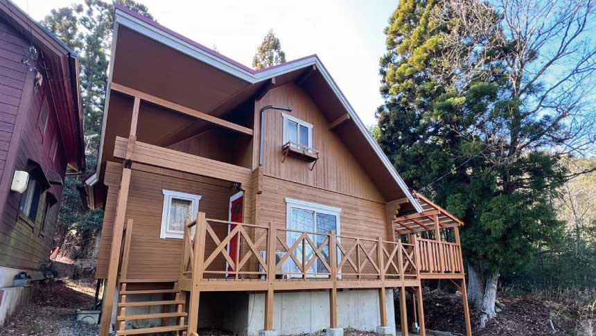 緑豊かな自然に囲まれた「ゆいま～るるり渓」の建物外観。広いウッドデッキ付きの木造コテージ。