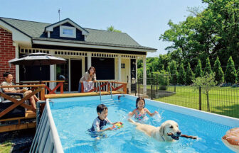 静岡県・伊豆高原の犬と泊まれる宿　ゆがふ「伊豆」｜レンガ調のコテージの庭にあるプライベートプールで、子供たちとゴールデンレトリバーが一緒に水遊びをしている様子。テラスでは大人がくつろぎ、家族全員で夏休みを満喫している