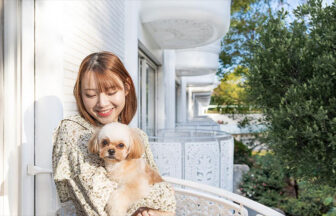 東京都の愛犬と泊まれる宿「グランドプリンスホテル新高輪」｜客室バルコニーで、愛犬のシーズー（小型犬）を抱っこして笑顔を見せる女性