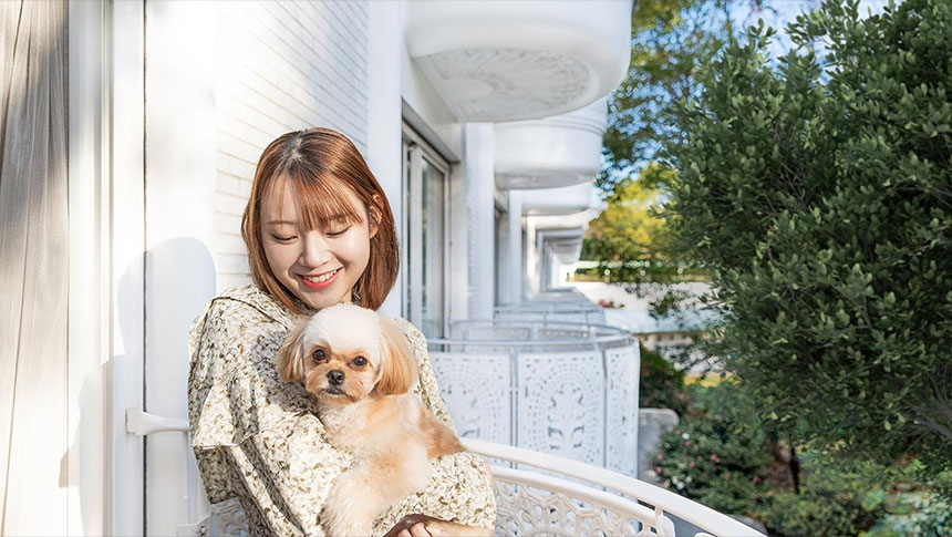 東京都の愛犬と泊まれる宿「グランドプリンスホテル新高輪」｜客室バルコニーで、愛犬のシーズー（小型犬）を抱っこして笑顔を見せる女性
