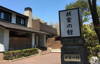 栃木県那須湯本にある、愛犬と泊まれる宿「伏楽の館 那須湯本店」の玄関と大きな看板。青空の下、周囲の緑に囲まれた趣のある建物が、愛犬との特別な旅の始まりを告げます。
