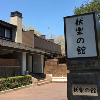 栃木県那須湯本にある、愛犬と泊まれる宿「伏楽の館 那須湯本店」の玄関と大きな看板。青空の下、周囲の緑に囲まれた趣のある建物が、愛犬との特別な旅の始まりを告げます。