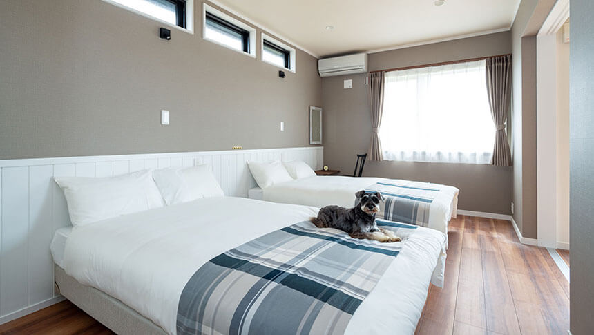 千葉県の愛犬と泊まれる宿「ASOVILLA KURO（アソヴィラ クロ）」犬連れ旅行におすすめの宿「ASOVILLA KURO」のベッドルーム。セミダブルベッドが2台並び、愛犬（シュナウザー）がくつろいでいる様子