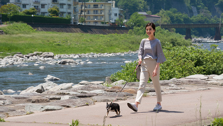 岐阜県・下呂温泉の愛犬と泊まれる宿「紅葉館 別館わん泊亭」近くの川沿いを愛犬のチワワとお散歩する女性