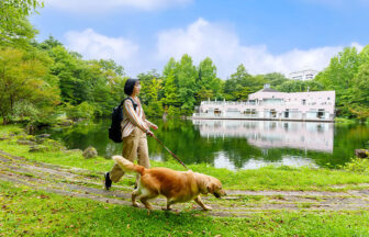 栃木県・那須の愛犬と泊まれるホテル「ホテルエピナール那須」の敷地内にある池のほとりを愛犬と散歩する女性