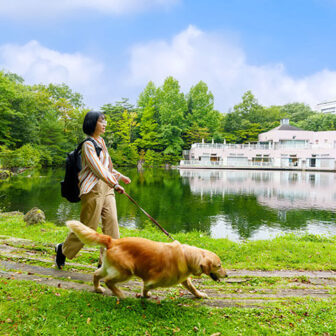 栃木県・那須の愛犬と泊まれるホテル「ホテルエピナール那須」の敷地内にある池のほとりを愛犬と散歩する女性