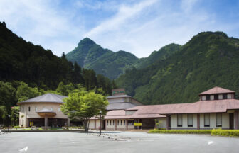 自然豊かな緑と山々に囲まれた「わんわんパラダイス 松阪」の建物外観と広々とした駐車場