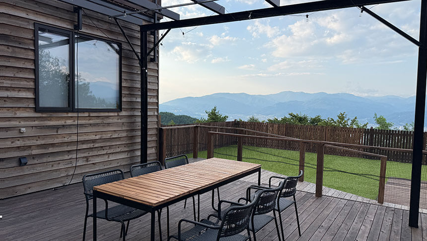 長野県・諏訪の愛犬と泊まれる宿「INU邸 SKY TERRACE SUWA」諏訪湖と山々の絶景を見渡すウッドデッキテラスとダイニングテーブル