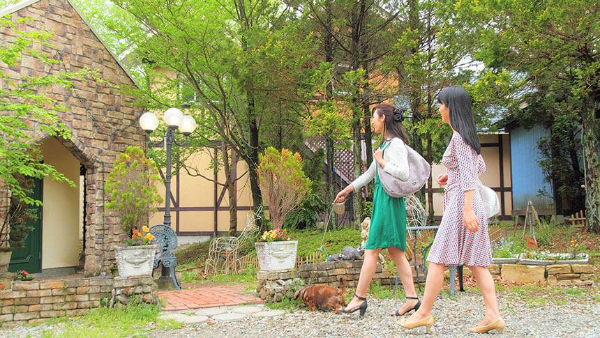 栃木県・那須高原の愛犬と泊まれる宿「アニマーレ プレミアム in 那須」の自然豊かな敷地内を愛犬とお散歩する女性ゲスト