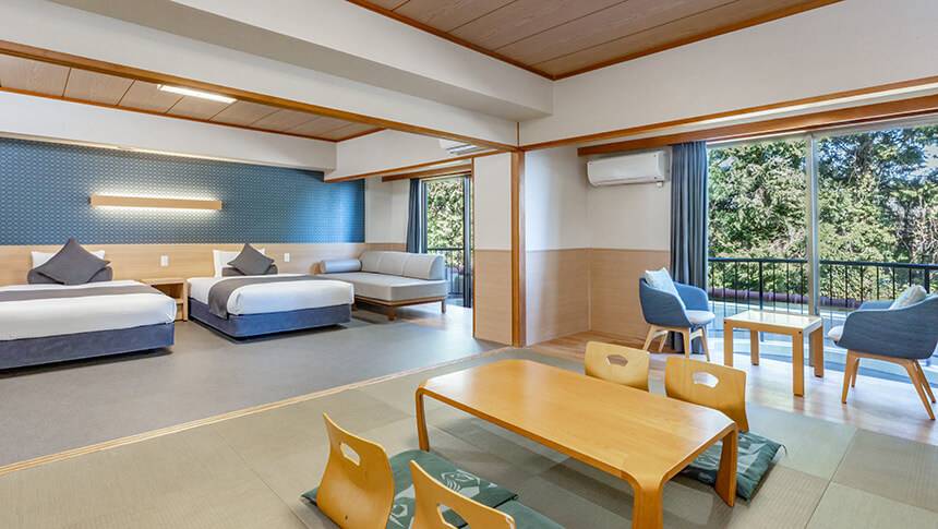 畳の落ち着いた和の空間と、ベッドの洋の快適さを併せ持つ和洋室。愛犬がのんびりと寝転べる広さがあり、家族みんなでくつろげるスタイル。窓から見える景色とともに、非日常の時間を楽しめます。｜犬と泊まれる静岡県のホテル｜わんわんパラダイス プレミア 伊豆高原　旧：Wan's Resort　城ヶ崎海岸