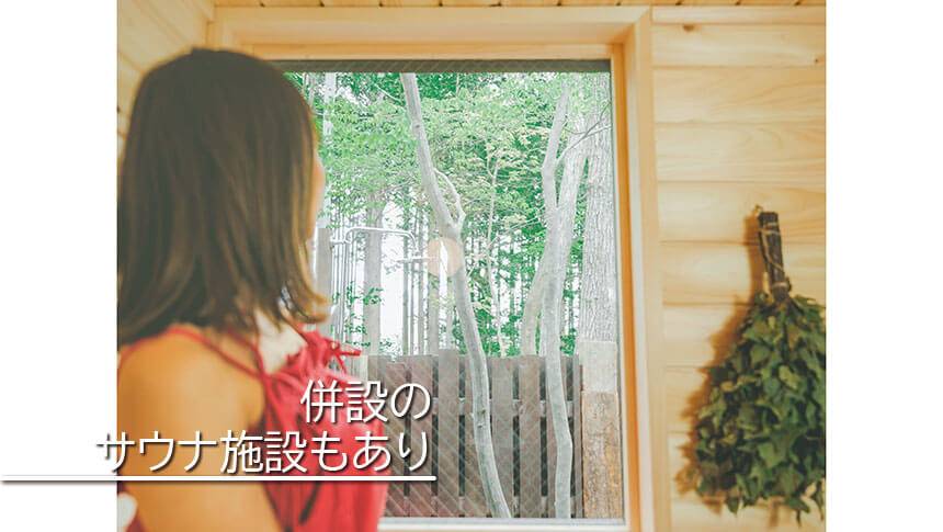 栃木県・那須にある愛犬と泊まれる宿ミモザ・リトリート那須の併設バレルサウナ施設内から緑豊かな森林の景観を眺める女性（栃木県那須町）