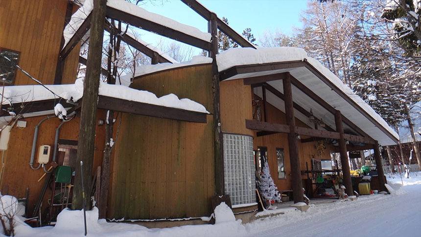 長野県の白馬村にある愛犬と泊まれる宿「ヴィラ・モノクローム」｜雪に覆われたヴィラの外観。屋根や地面に深い積雪があり、冬の晴天の下で撮影された様子。