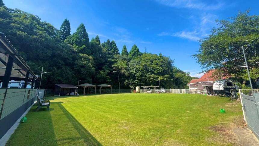 プールの脇にある青空の下に広がる開放感あるドッグランと自然豊かな宿の風景｜犬と泊まれる兵庫県淡路島の宿｜広大な天然芝のドッグランとプールが魅力！｜ガーデンリゾート淡路島