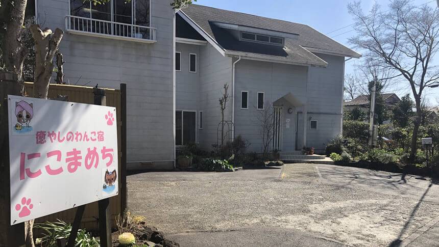 静岡県・伊豆高原にある愛犬と泊まれる宿「にこまめち」の白い建物外観と看板