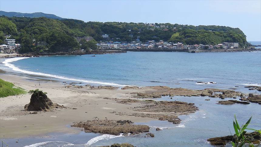 静岡県・河津温泉にある犬と泊まれる宿「河津　花小町」｜旅館の近くに広がる今井浜海岸の風景。青い海と砂浜、岩場が見渡せ、遠くには緑豊かな山々と町並みが広がっている。
