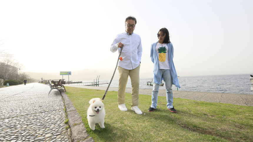 湖畔の遊歩道を仲良く散歩するポメラニアンと夫婦。自然に囲まれた環境でペットと楽しむ癒しの休日。｜犬と泊まれる北海道の宿｜源泉至近の温泉が自慢｜ゆとりろ洞爺湖