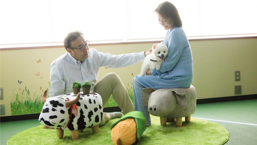 夫婦に抱かれながら嬉しそうなポメラニアン。ペットと家族で過ごすアットホームな宿泊体験が叶うペット宿。｜犬と泊まれる北海道の宿｜源泉至近の温泉が自慢｜ゆとりろ洞爺湖