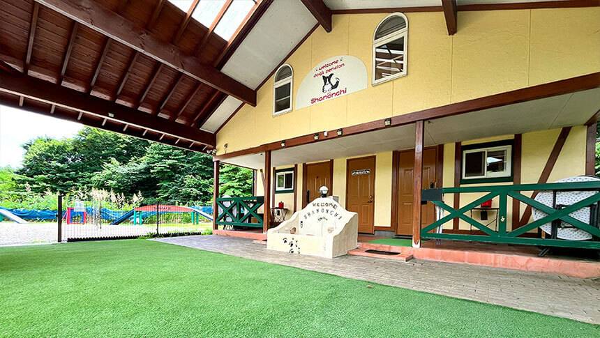 栃木県の那須・板室にある愛犬と泊まれる宿「dog’s pension しゃのんち」｜客室の建物の外観と、その前に広がるウッドデッキや芝生の様子に見えます